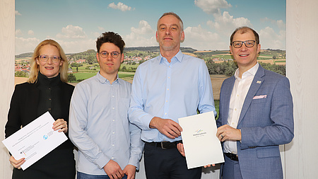 Vier Personen präsentieren einen Förderbescheid.