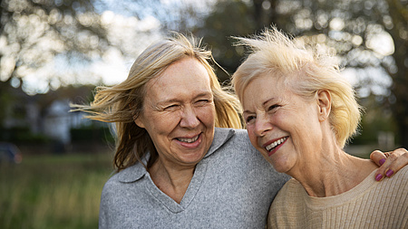 Zwei ältere Frauen Arm in Arm, lachend in der Natur