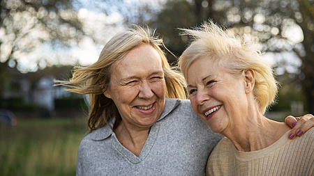 Zwei ältere Frauen Arm in Arm, lachend in der Natur