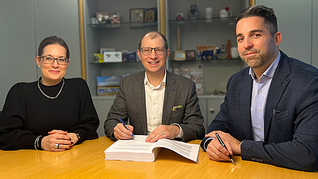 Landrat Jan Weckler, Tobias Pflüger und Katja Müller-Lind sitzen an eine Tisch. Vor ihnen ein Dokument.