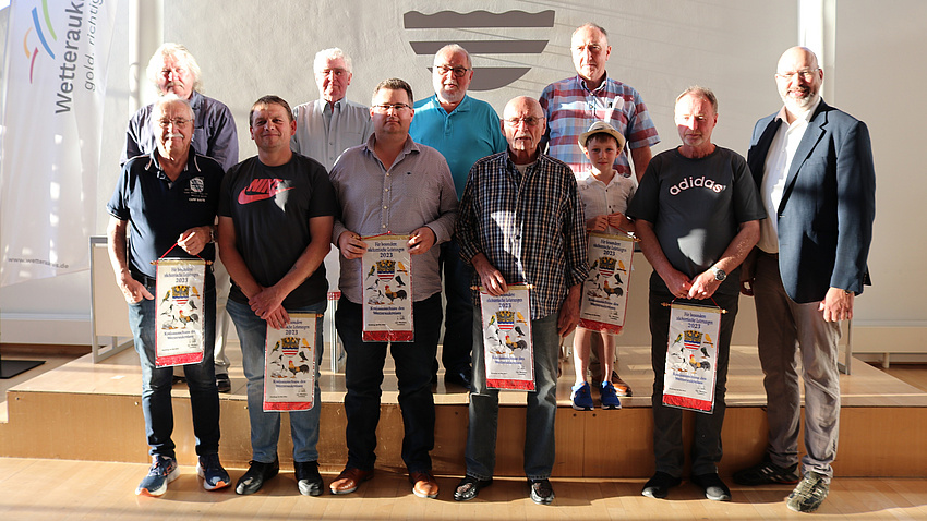 Mehrere Menschen stehen in einem Saal und halten Urkunden in den Händen.