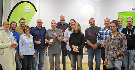 Eine Gruppe von Menschen steht in einem Raum und lächelt in die Kamera.