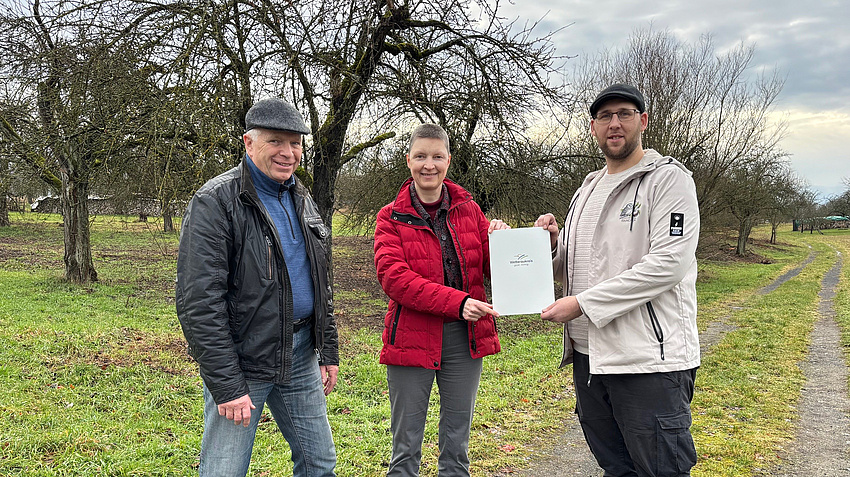 Der 1. Vorsitzende des  Traditionsvereins Hainchen e.V. Chris Marvin Wolf (rechts) und Vereinsmitglied Thomas Zinn nehmen den Bescheid von Sozialdezernentin Marion Götz entgegen.