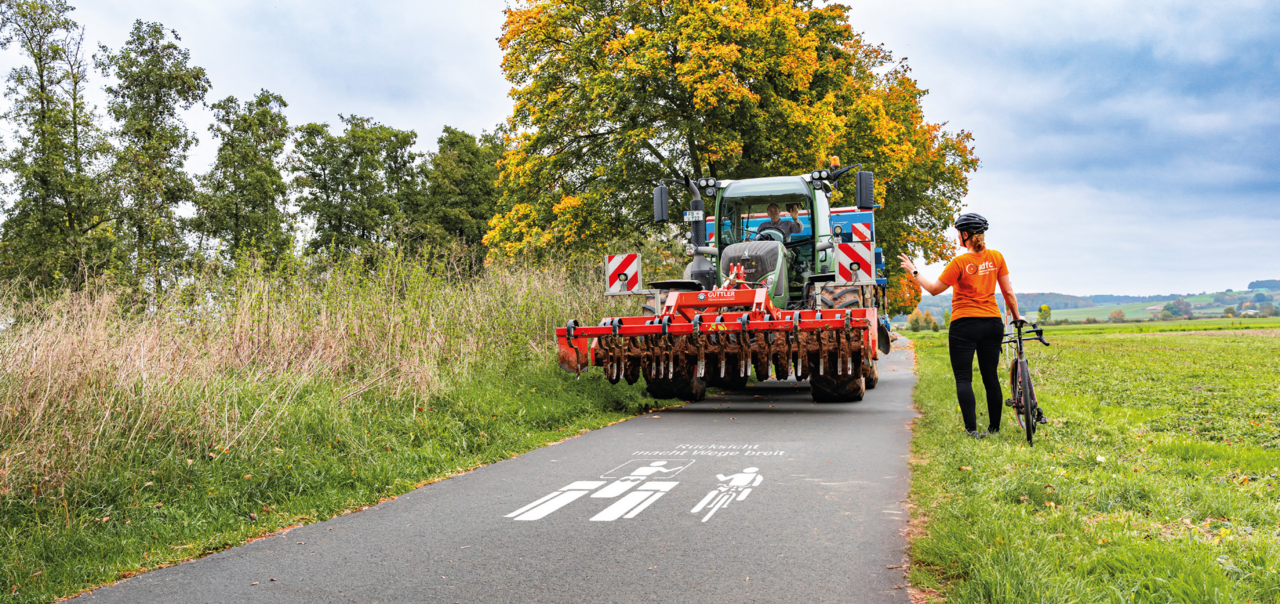 Radfahrer macht Platz für einen TRaktor.