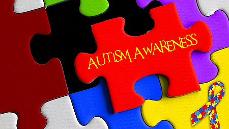 Zu sehen sind mehrere verschiedenfarbige, ineinandergreifende Puzzleteile. Auf einem von ihnen steht der englische Begriff für "Autismus".