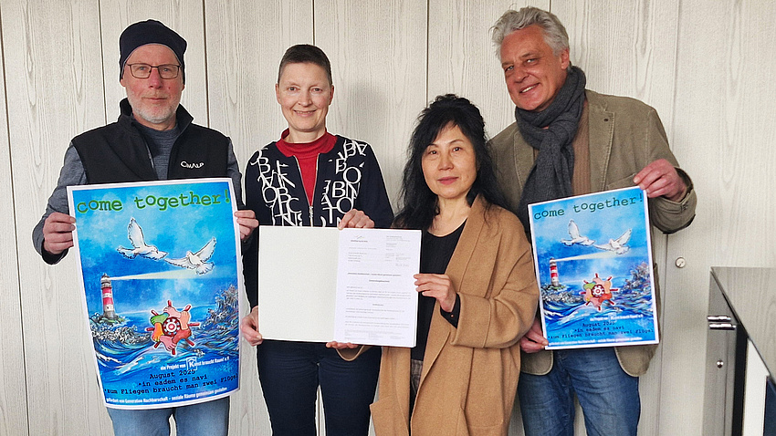 Zwei Frauen und zwei Männer halten Plakate in die Kamera.