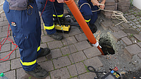 Personen mit blauer Uniform untersuchen ein Loch im Boden.