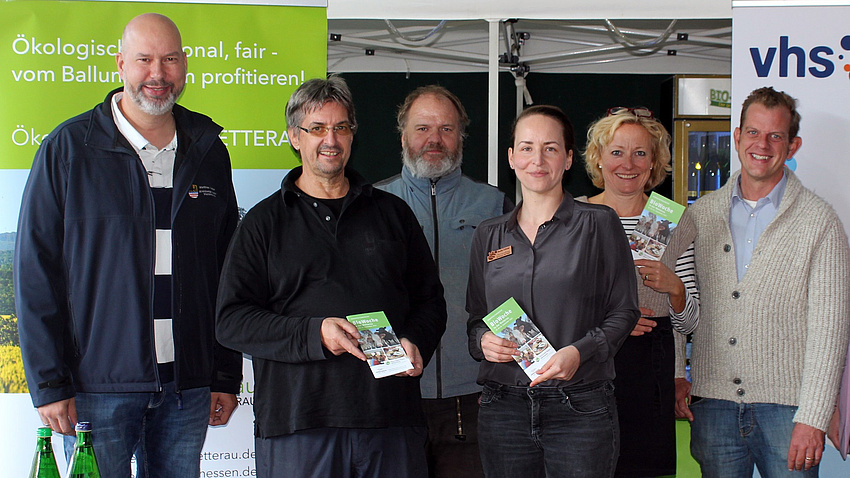 Zwei Frauen und vier Männer stehen nebeneinander und lächeln in die Kamera.