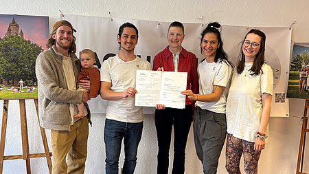 Fünf Personen halten ein Dokument in die Kamera.