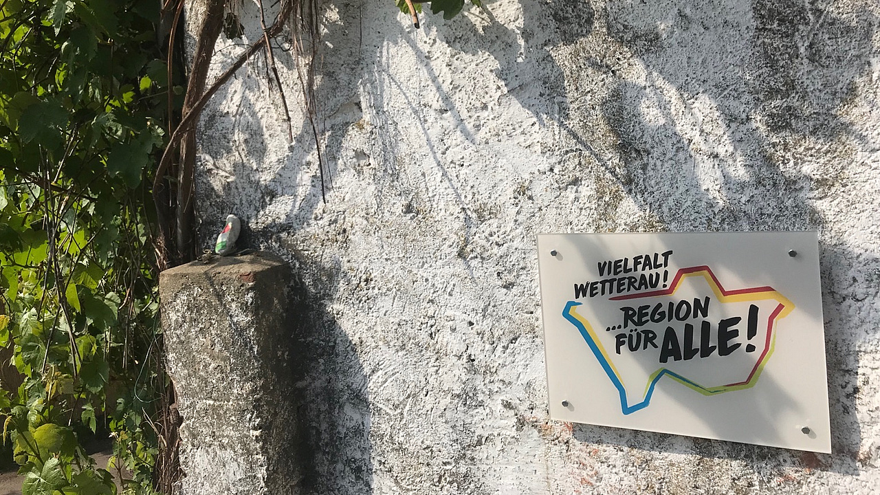 Mauer mit einem Schild mit der Beschriftung: Vielfalt Wetterau. Region für alle.