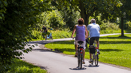 Ein Mann und eine Frau sind auf Fahrrädern in einem Park unterwegs.