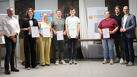 Junge Menschen halten eine Urkunde in die Kamera.