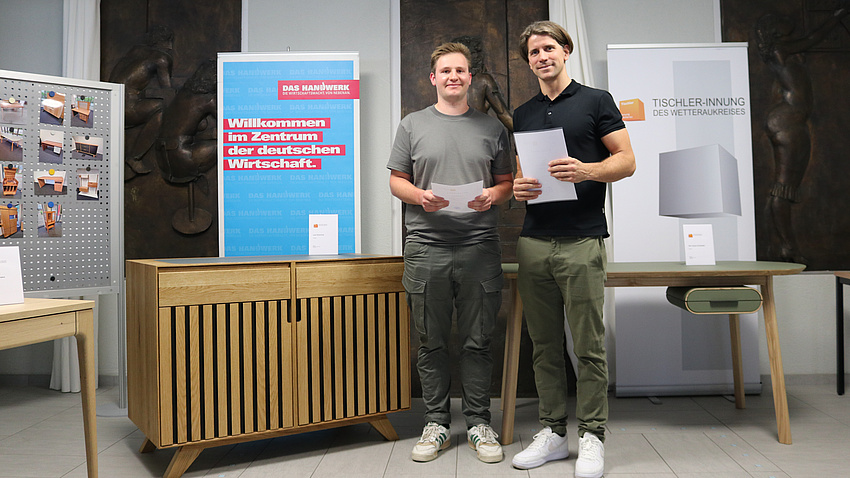 Zwei Menschen stehen vor einem hölzernen Kaffeetisch.