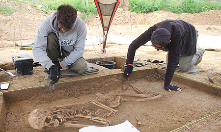 Zwei Männer graben ein historisches Skelett aus