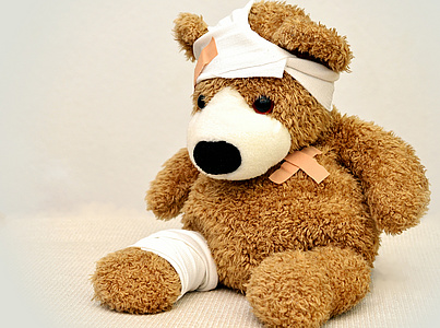 Ein Stoffteddybär mit Pflaster und Bandagen am Bein und am Kopf.