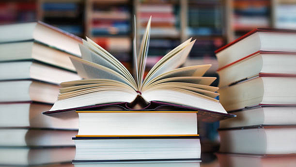Aufgeschlagenes Buch auf mehreren anderen Büchern.