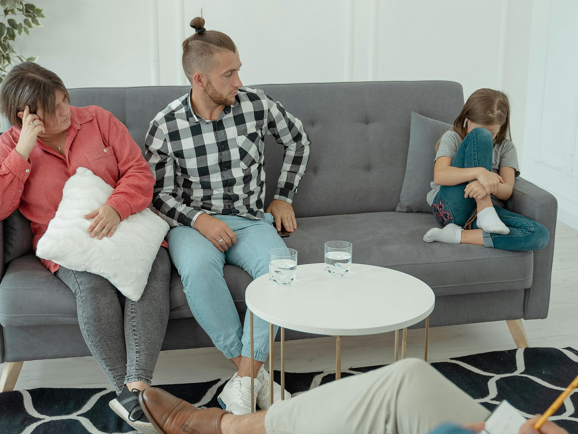 Eltern mit Kind auf einem Sofa, Kind wendet sich ab