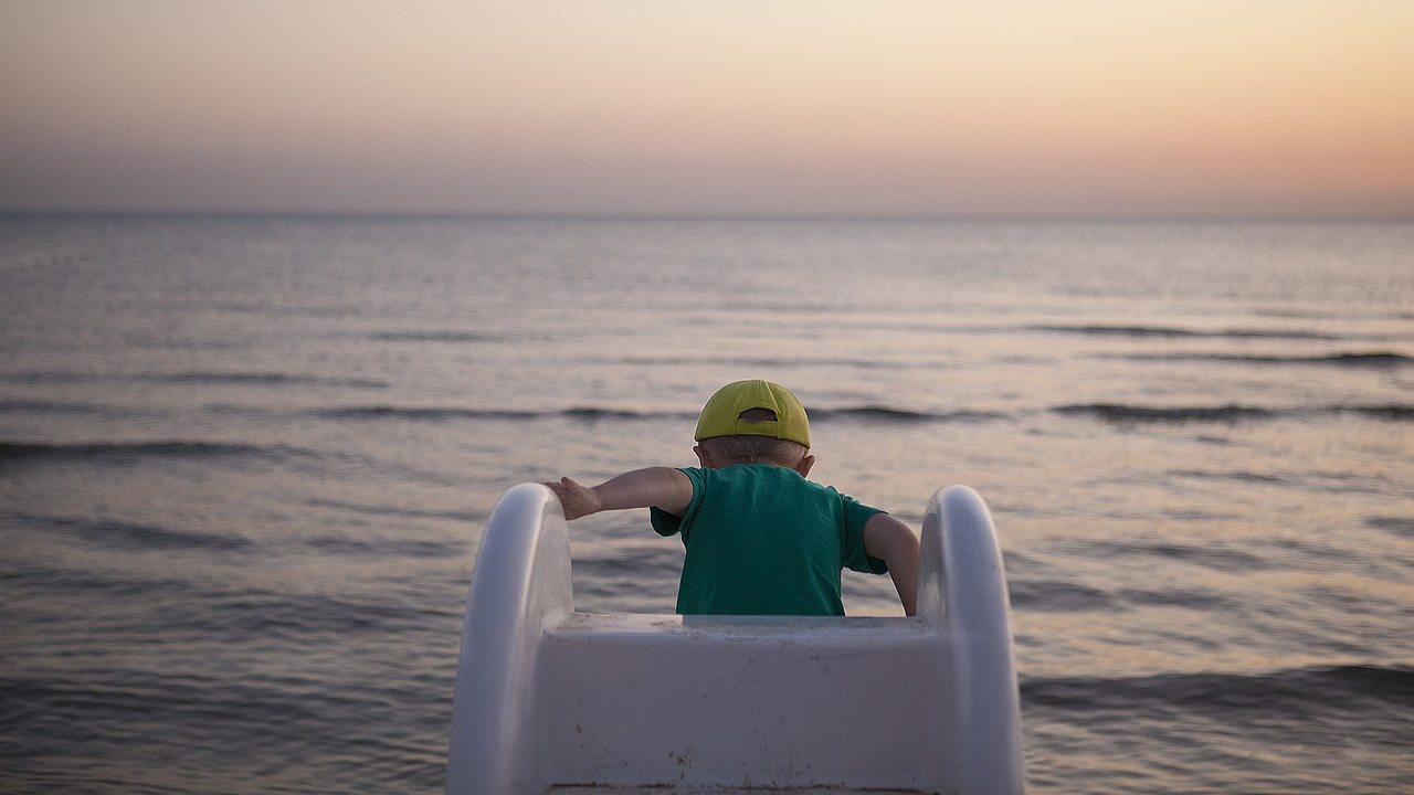 Kind rutscht auf einer Rutsche ins Wasser 