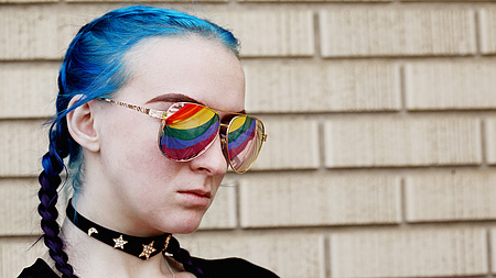 Das Foto zeigt eine junge Frau mit Regenbogenbrille.