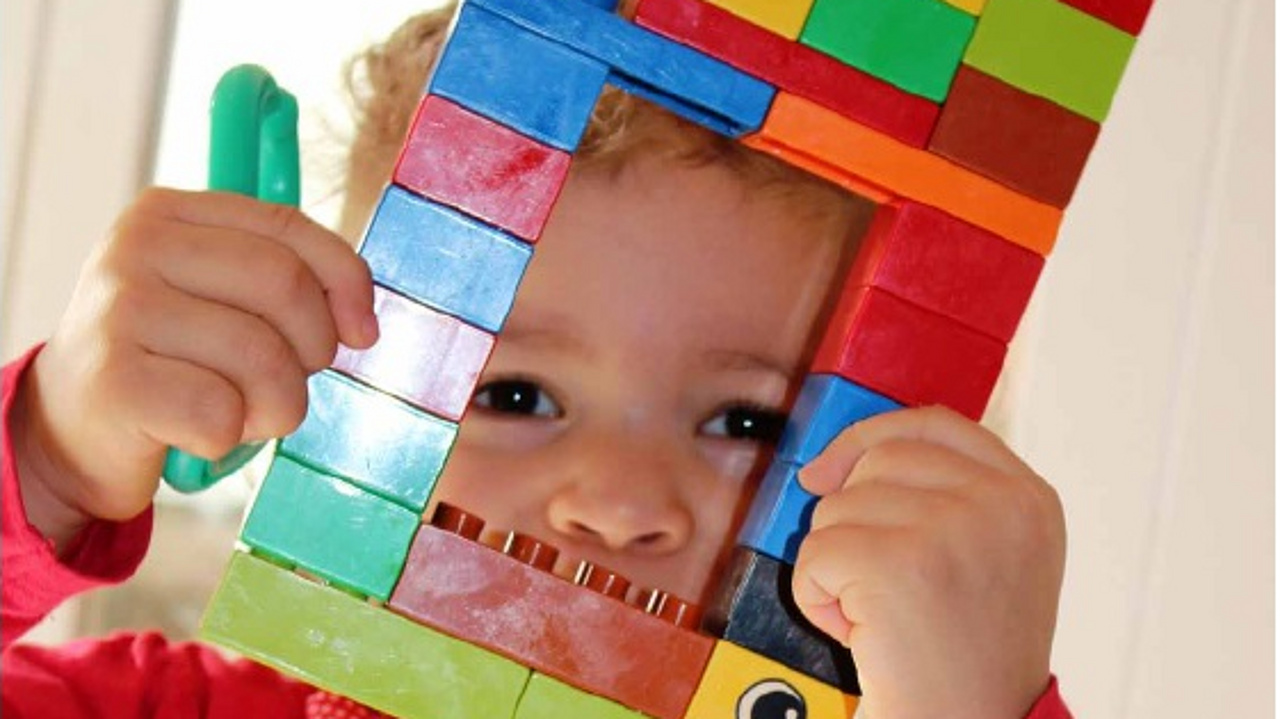 Kind schaut durch einen gebauten Lego-Bilderrahmen
