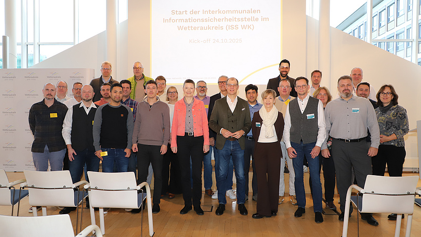 Zahlreiche Frauen und Männer haben sich in einem großen Saal für ein Foto aufgestellt.