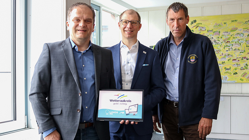 Drei Männer zeigen eine App auf einem iPad.