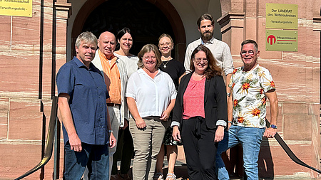 Eine Gruppe von Menschen steht auf einer Eingangstreppe.