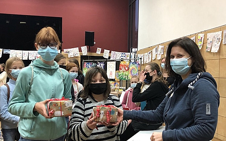 Zwei Mädchen mit Masken halten Päckchen in ihren Händen.