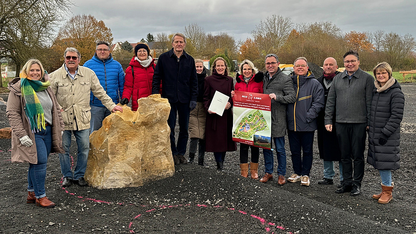 Eine Gruppe von Leuten lächelt in die Kamera. Sie halten ein Dokument in der Hand.