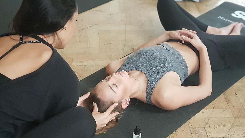 Eine Yogalehrerin und eine Frau auf einer Yogamatte.