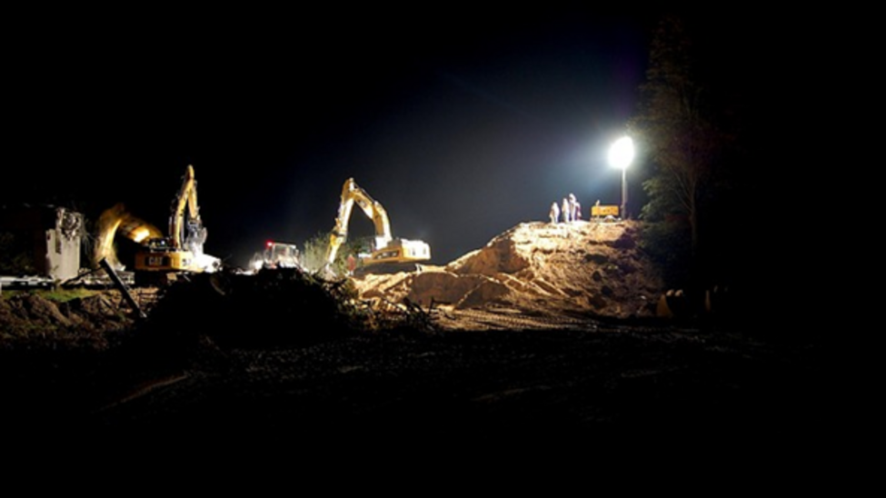 Arbeitende Bagger bei Nacht unter Beleuchtung