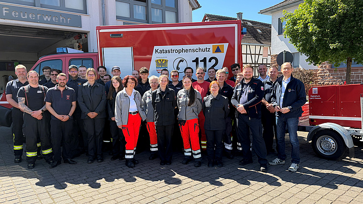 Eine große Gruppe Menschen steht vor einem Feuerwehrauto mit der Aufschrift Katastrophenschutz und dem Wappen des Wetteraukreises. .