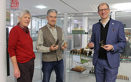 Drei Personen stehen vor der Vitrine mit den Schachfigueren