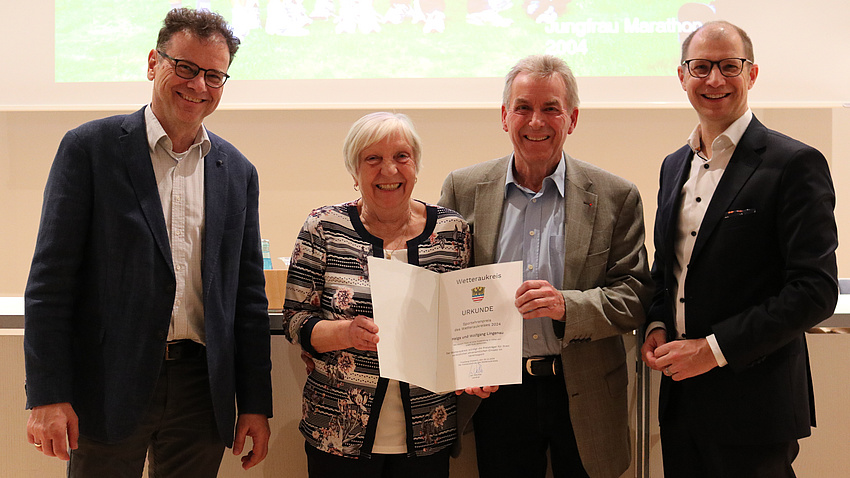 Landrat Jan Weckler und Kreistagsvorsitzender Armin Häuser überreichen Helga und Wolfgang Lingenau die Urkunde.
