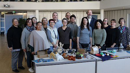 Einige Männer und Frauen stehen hinter zwei Tischen, auf denen verschiedene Utensilien zum Thema Klima liegen.