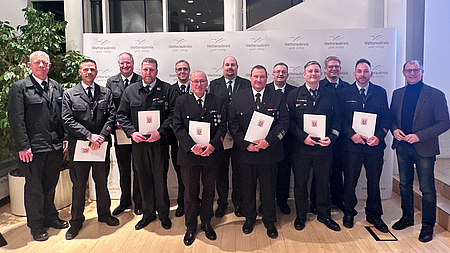 Mehrere Personen halten Urkunden in den Händen und schauen in die Kamera.