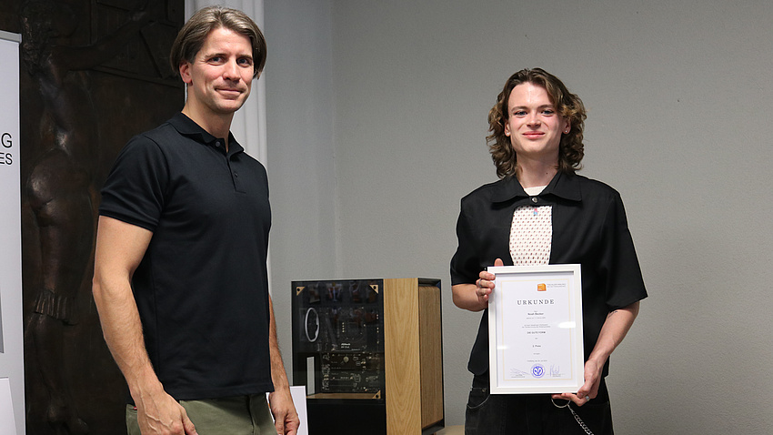 Zwei Menschen stehen vor einem Computergehäuse.