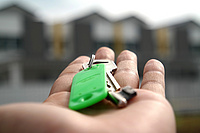 Eine Hand hält einen Schlüssel mit einem grünen Schild.