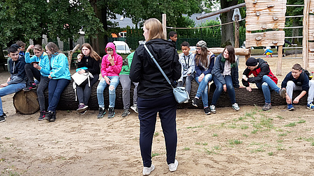 Eine Person steht mit dem Rücken zum Betrachter.  Im Hintergrund eine Gruppe Jugendlicher.