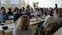 Personen im Saal hören einem Vortrag zu