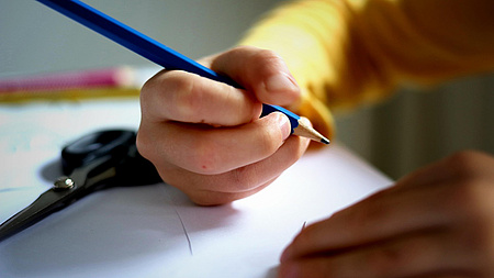 Ein Kind mit einem Bleistift in der Hand.