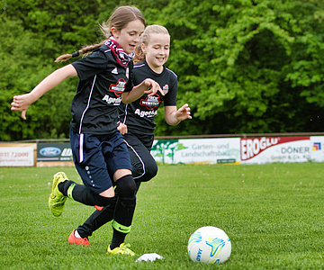 Zwei Mädchen in Trikots spielen eine Ball