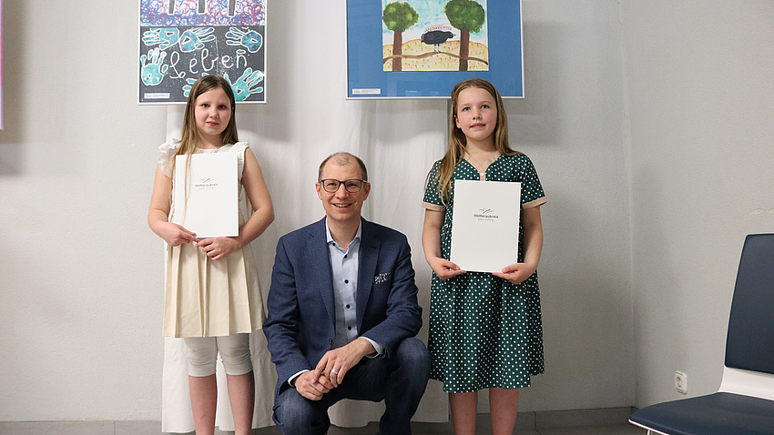 Drei Menschen stehen vor zwei Gemälden.