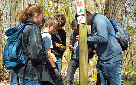 Eine Gruppe Jugendlicher mit GPS-Geräten im Wald.