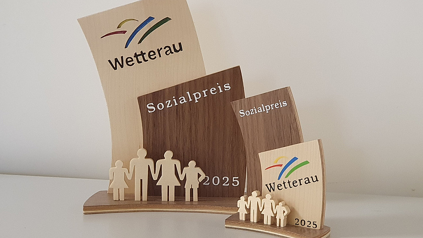 Zwei Trophäen aus Holz. Auf ihnen steht "Sozialpreis Wetterau".