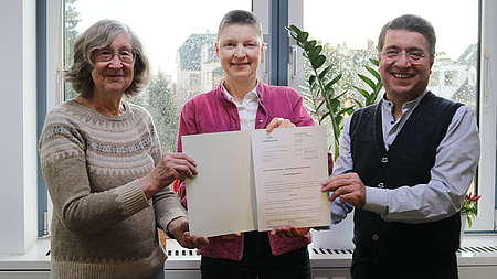 Marion Götz übergibt den Förderbescheid an Mehmet Turan und Beate Neuwirth.