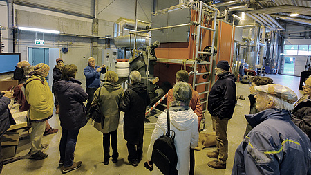 Mehrere Personen vor einer großen Heizungsanlage.