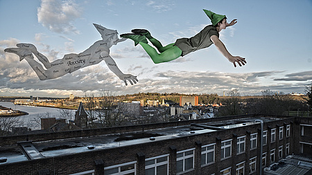 Eine Zeichentrickfigur Peter Pan fliegt über die Dächer. Hinter ihm sein Schatten.